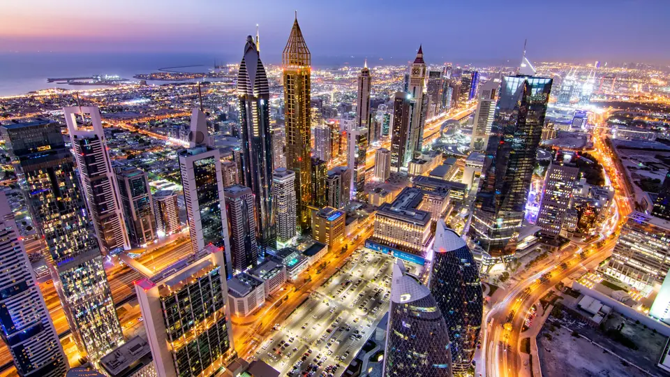 Downtown Dubai at dusk seen from above, towers lit and roads glowing