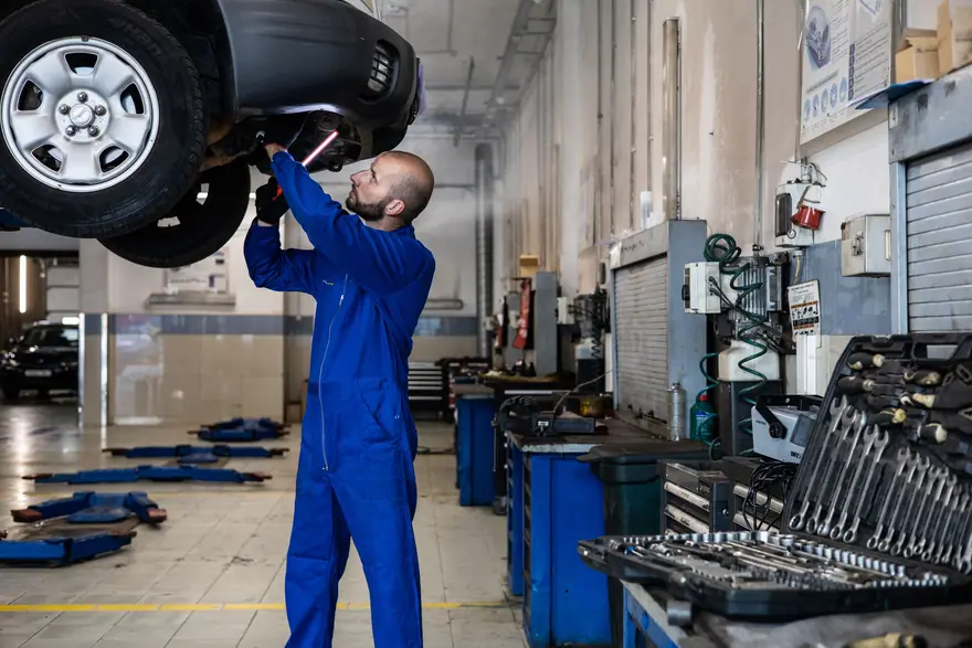 A technician works under a car raised on a lift in a clean service centre