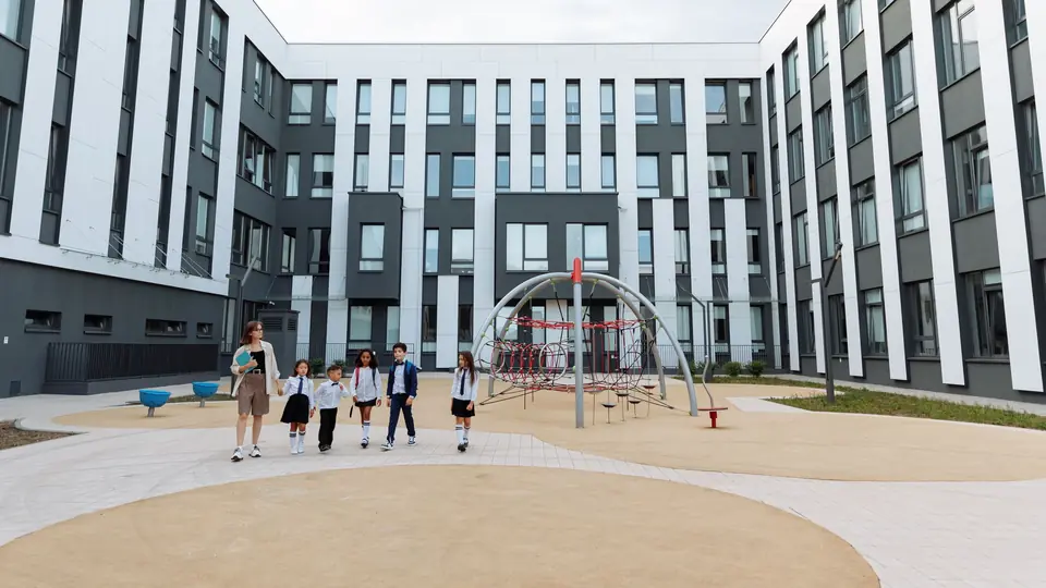 Children walk across the courtyard of a modern school building