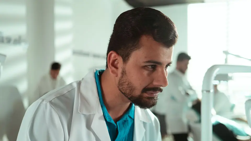 A doctor in a white coat looks across a busy dental clinic floor