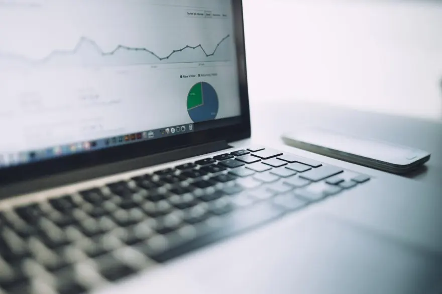 Laptop on a desk showing a traffic graph and a pie chart