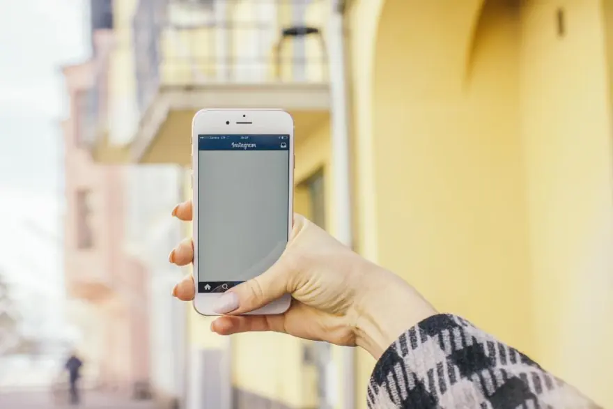 A hand holding up a phone with Instagram open