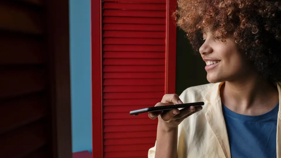 A woman holds her phone flat in front of her and records a voice message