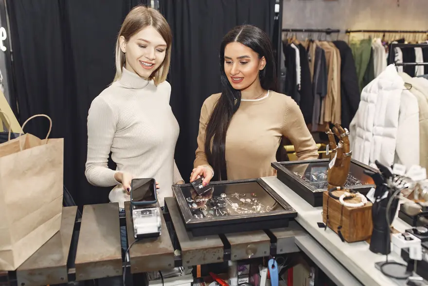 A sales adviser shows a client pieces from a jewellery tray at a boutique counter