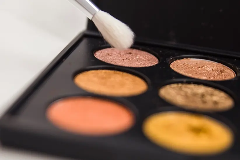 An eyeshadow palette with a makeup brush