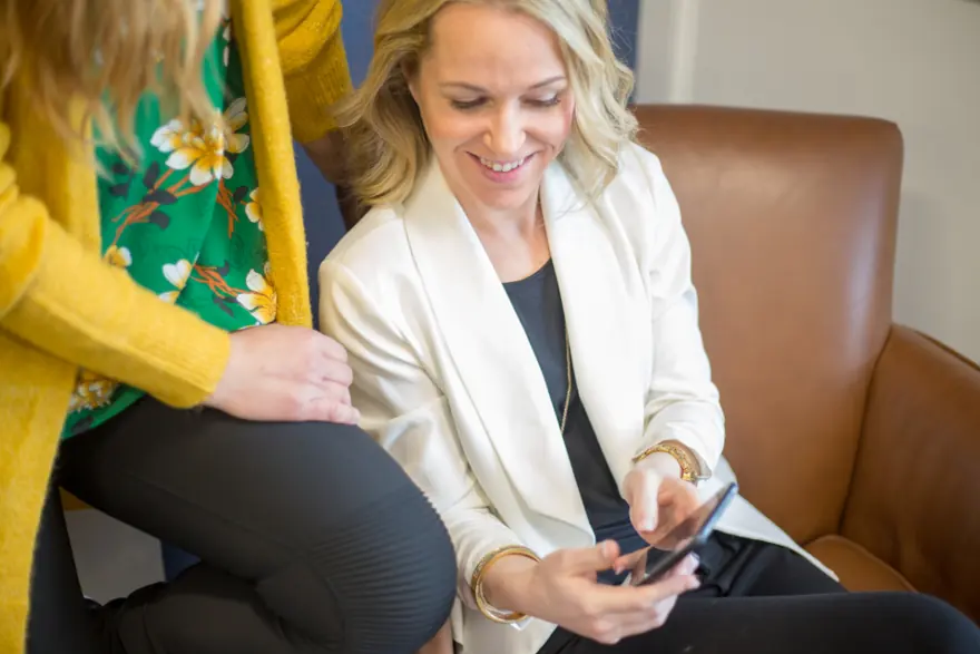 A woman on a sofa smiling at her phone