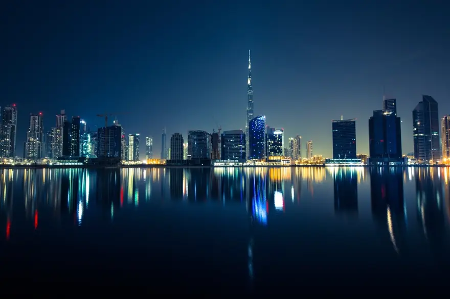 The Dubai skyline at night, reflected in the water