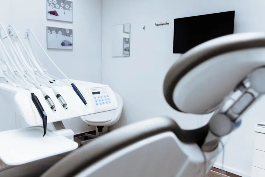 An empty treatment chair and instruments in a bright clinic room