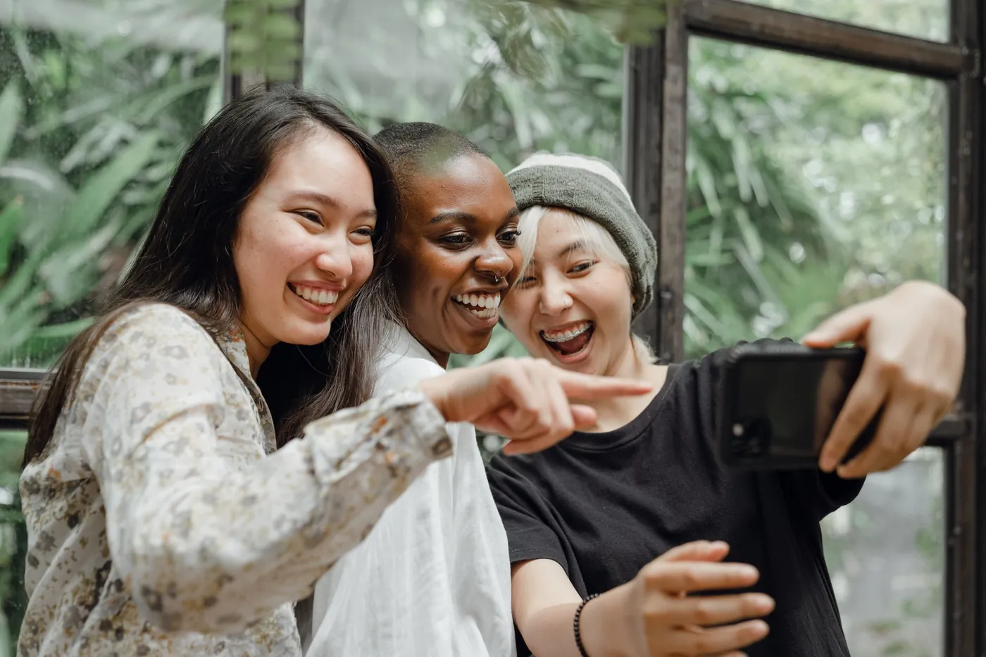 Three friends laughing together at something on a phone