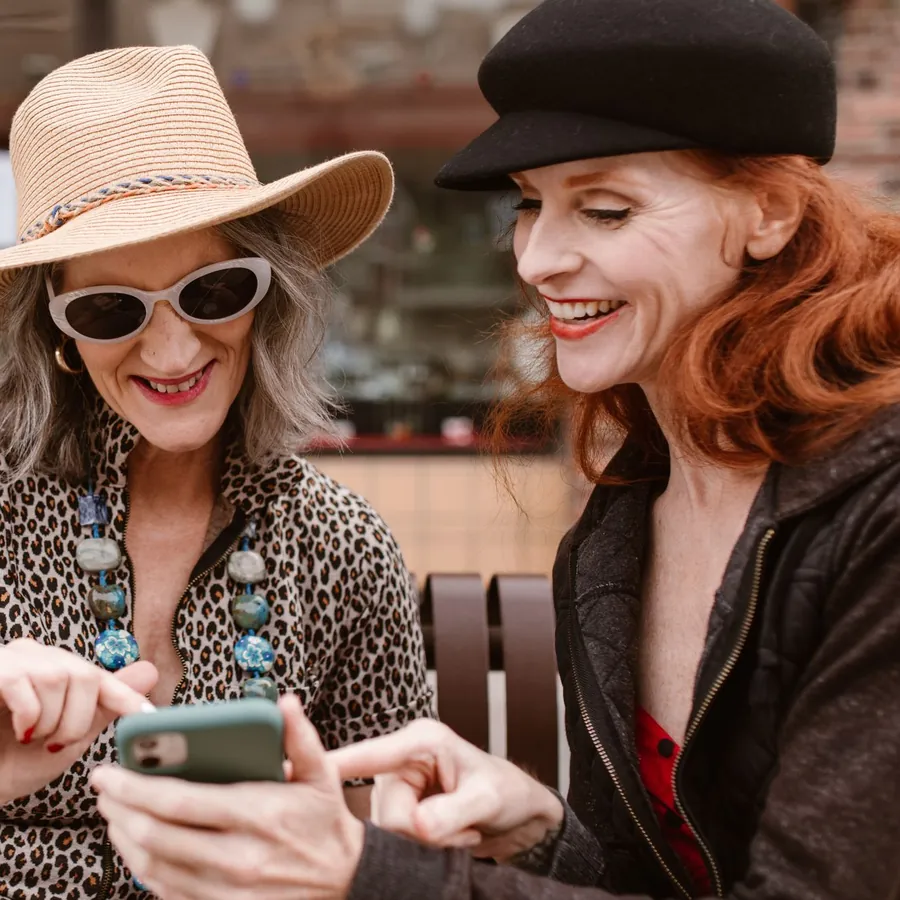 Two friends in hats laughing over a phone