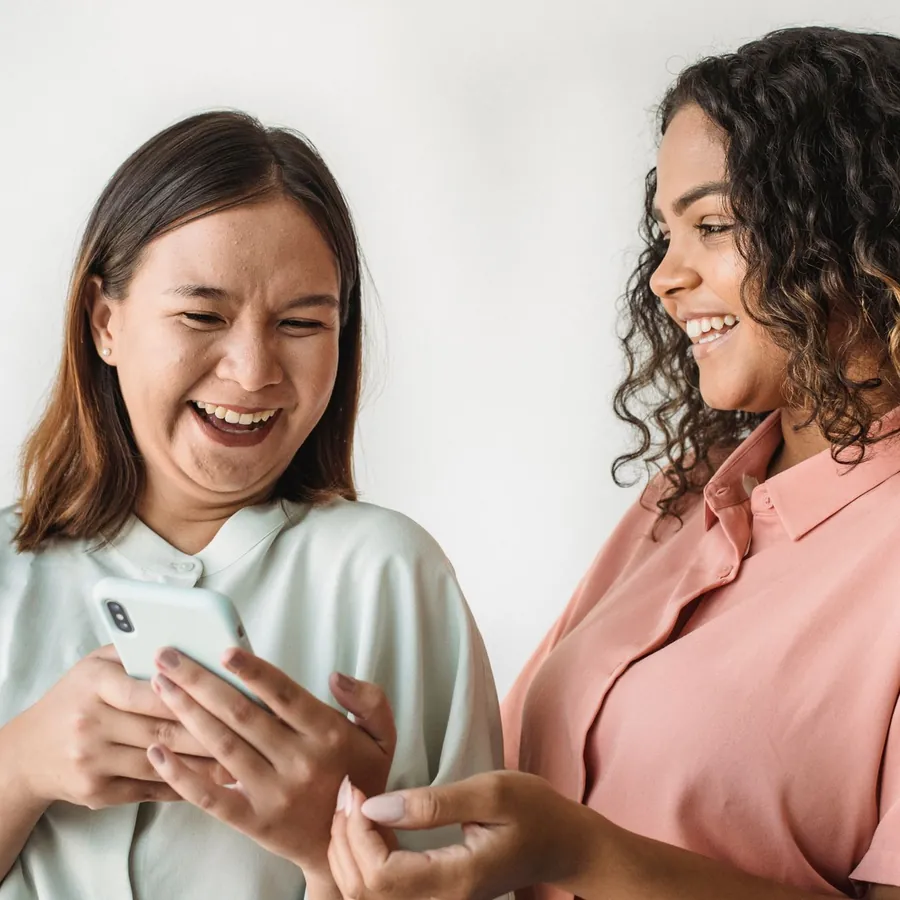 Two friends laughing at a message on a phone