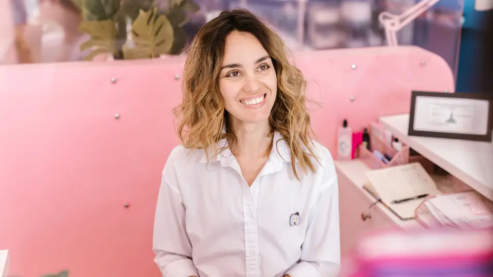 A smiling receptionist at a pink front desk