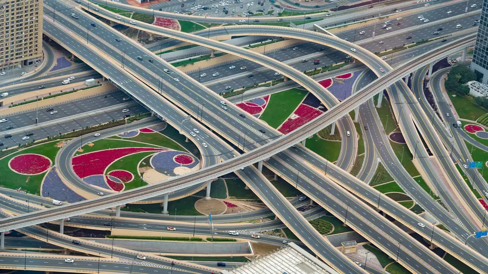 Aerial view of a multi-level road interchange in Dubai with traffic and landscaped verges
