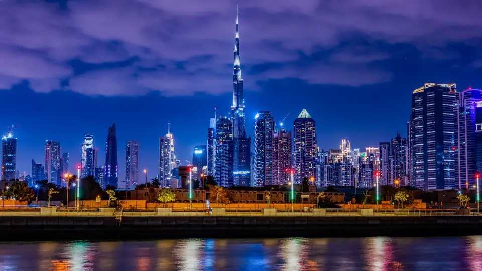 Burj Khalifa and the Downtown Dubai skyline lit up at dusk, reflected in the water