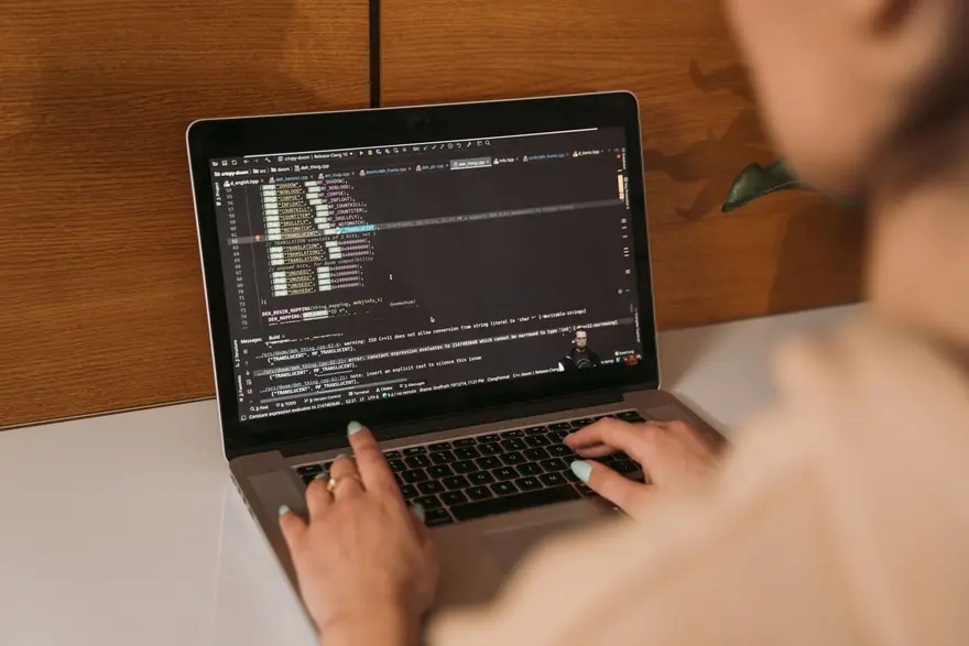 A developer types on a laptop showing a code editor