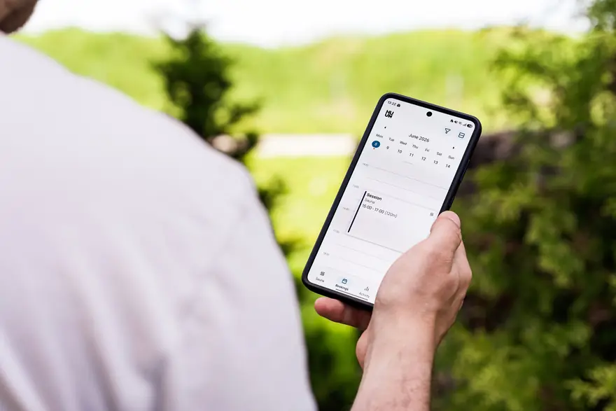 A hand holding a smartphone with a calendar app open