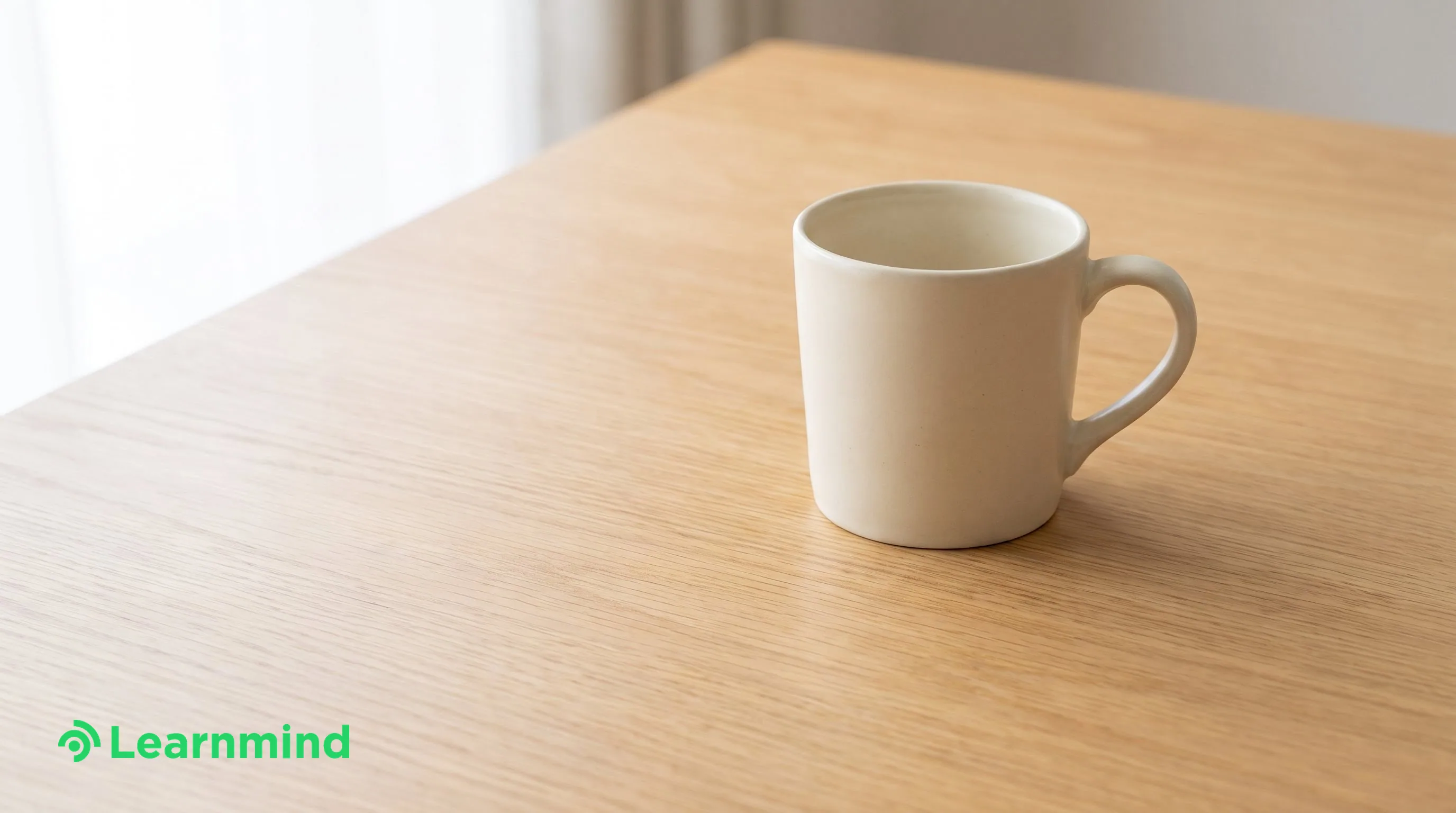 single cream ceramic mug on empty wood desk, bright daylight
